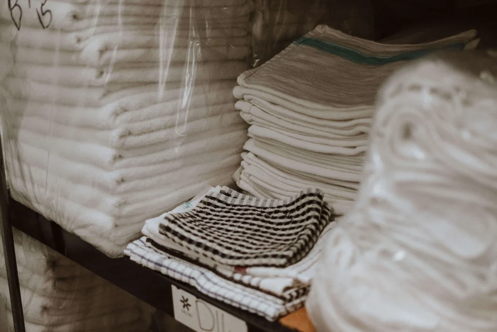 Folded table linen and kitchen cloths on the packing shelves